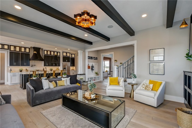 living room with a notable chandelier, light wood-type flooring, beamed ceiling, and decorative columns