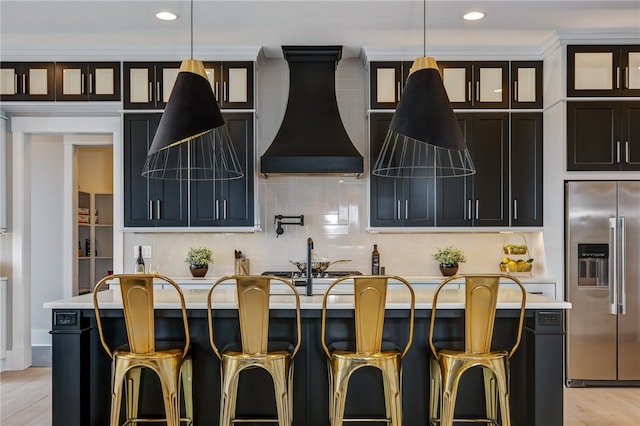 kitchen featuring light hardwood / wood-style floors, hanging light fixtures, high end refrigerator, and custom range hood