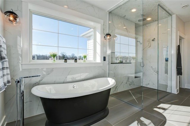 bathroom with plus walk in shower, tile patterned floors, and tile walls