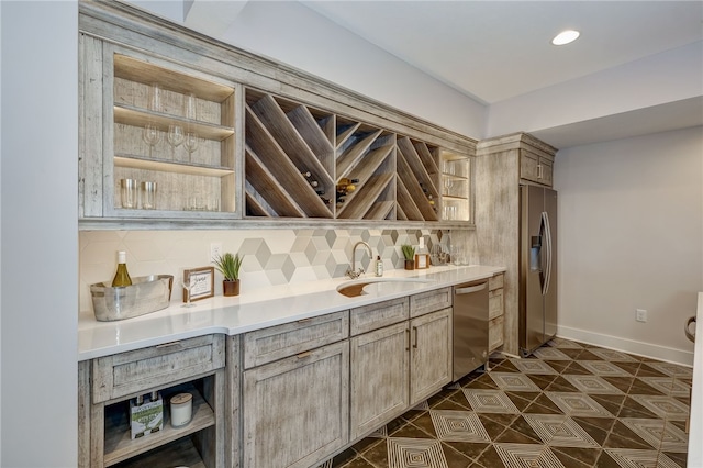 bar with light brown cabinetry, appliances with stainless steel finishes, sink, and decorative backsplash