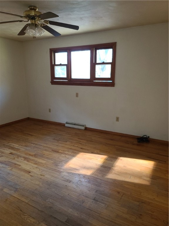 spare room with ceiling fan, a baseboard heating unit, and wood-type flooring