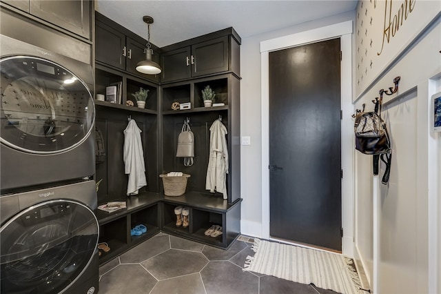 mudroom featuring dark tile patterned floors and stacked washing maching and dryer