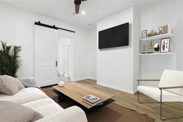 living room featuring a barn door, hardwood / wood-style floors, and ceiling fan