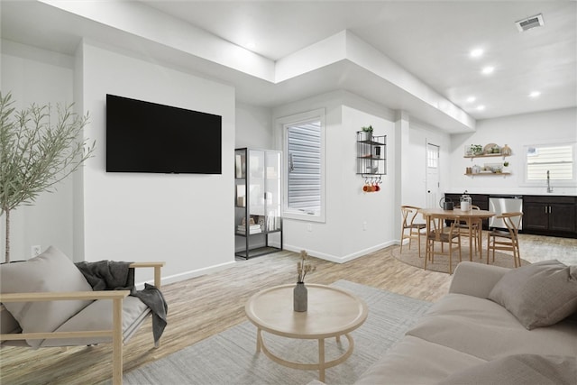 living room with light hardwood / wood-style floors and sink