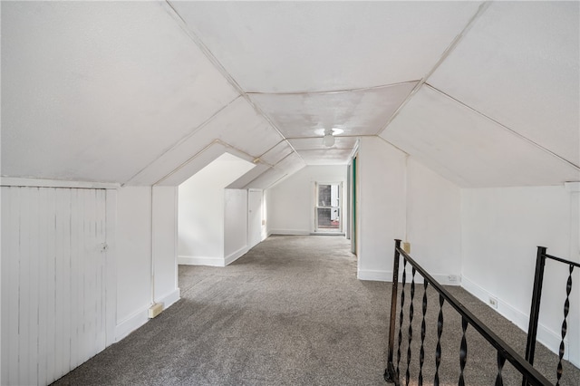 additional living space with carpet floors, wood walls, and vaulted ceiling