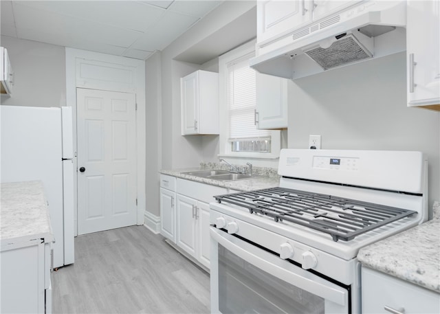 kitchen with white appliances, light hardwood / wood-style floors, white cabinets, and sink