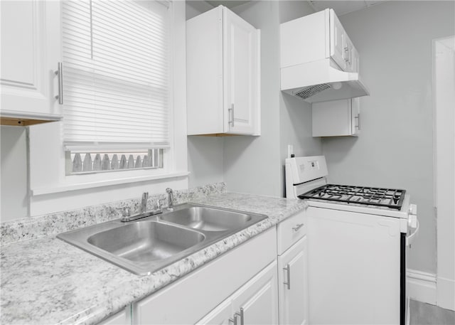 kitchen with white gas stove, exhaust hood, white cabinetry, and sink