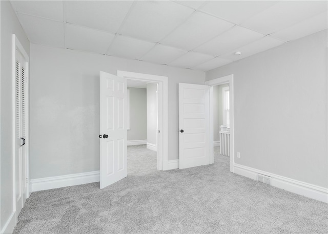 unfurnished bedroom featuring a paneled ceiling, a closet, and carpet