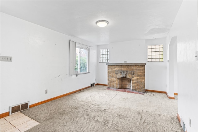 unfurnished living room featuring a brick fireplace and carpet