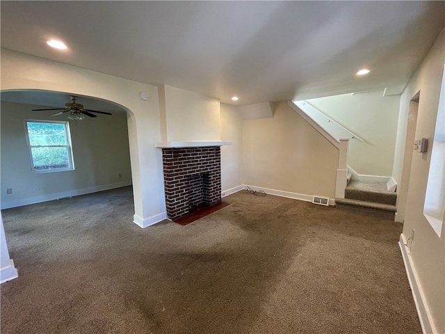 unfurnished living room with a fireplace, dark colored carpet, and ceiling fan