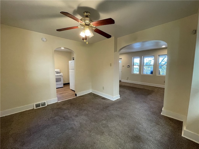 unfurnished room with ceiling fan and dark colored carpet