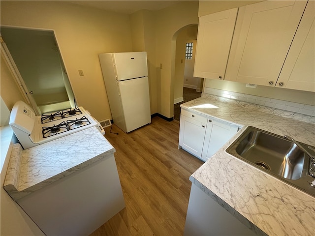 kitchen featuring sink, white appliances, white cabinetry, and light hardwood / wood-style flooring