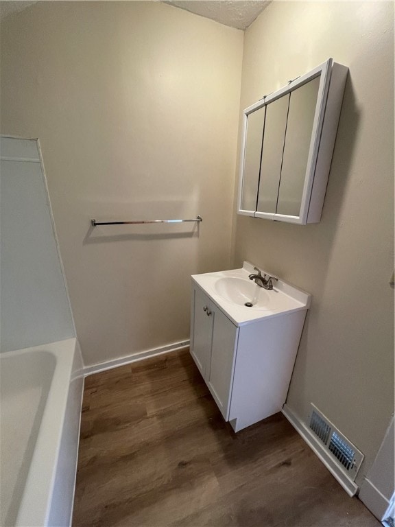 bathroom with hardwood / wood-style flooring, a bathing tub, and vanity