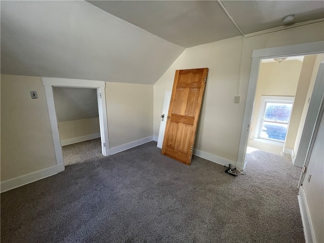 additional living space with dark colored carpet and vaulted ceiling