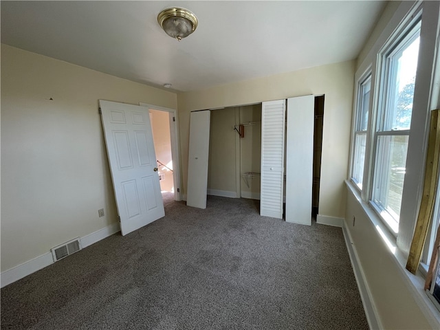 unfurnished bedroom with dark carpet, a closet, and multiple windows