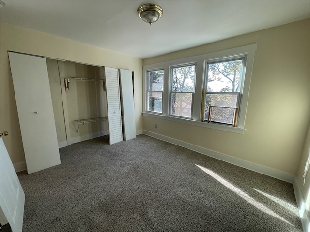 unfurnished bedroom featuring dark colored carpet and multiple closets