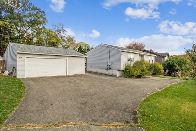 view of property exterior with a garage, an outbuilding, and a lawn