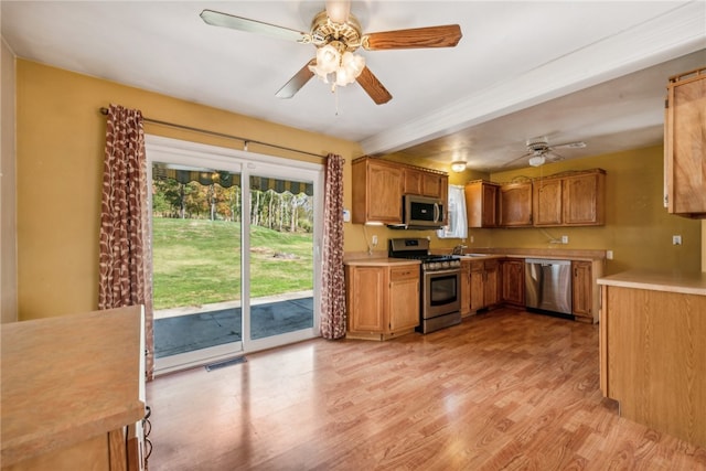 kitchen featuring appliances with stainless steel finishes, ceiling fan, beam ceiling, and light hardwood / wood-style flooring