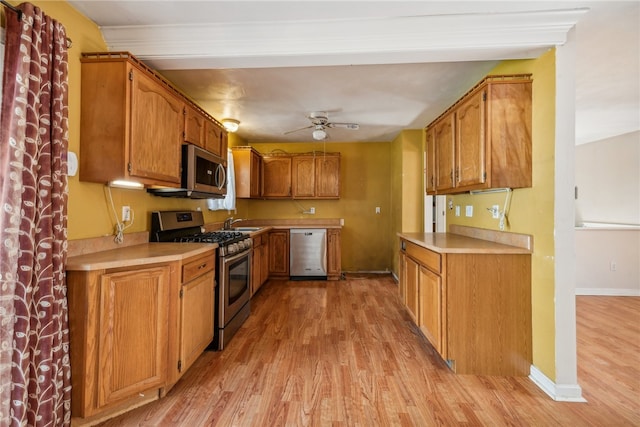 kitchen featuring crown molding, appliances with stainless steel finishes, sink, light hardwood / wood-style floors, and ceiling fan