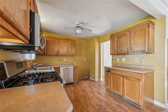 kitchen with appliances with stainless steel finishes, light hardwood / wood-style floors, ceiling fan, and sink