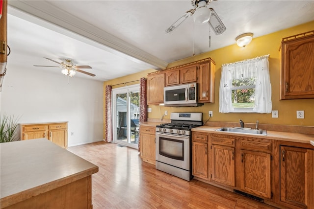 kitchen with appliances with stainless steel finishes, sink, ceiling fan, and light hardwood / wood-style flooring