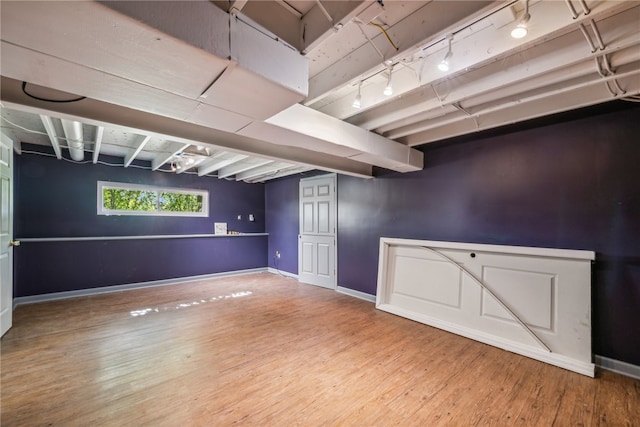 basement featuring wood-type flooring and track lighting