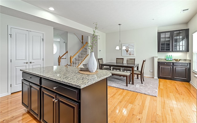 kitchen with light wood-type flooring, a healthy amount of sunlight, pendant lighting, and a center island