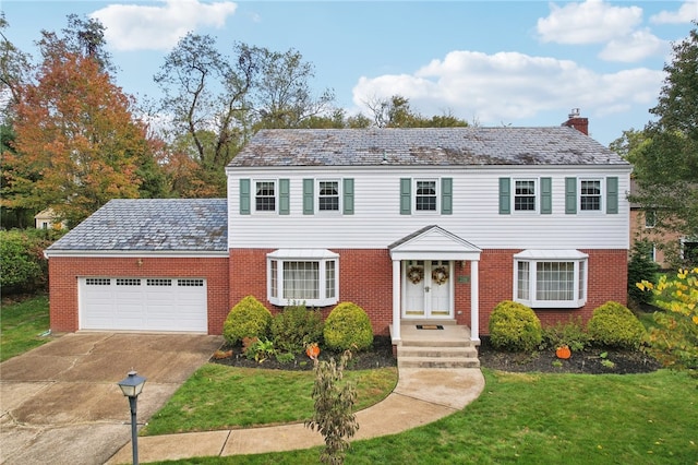 colonial inspired home with a front lawn and a garage