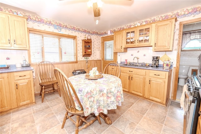 dining area featuring ceiling fan, sink, wooden walls, and a wealth of natural light