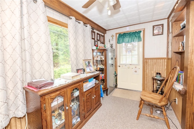 living area with wood walls, light carpet, and ceiling fan