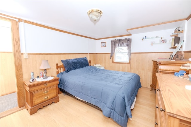 bedroom with ornamental molding, wooden walls, and light wood-type flooring