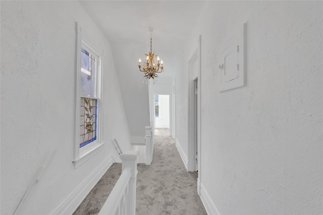 corridor with light carpet and a chandelier