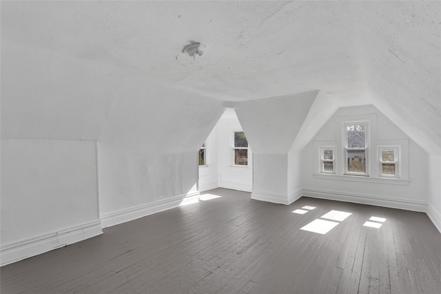 additional living space featuring dark wood-type flooring and vaulted ceiling