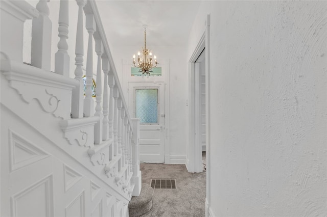 carpeted foyer with a chandelier