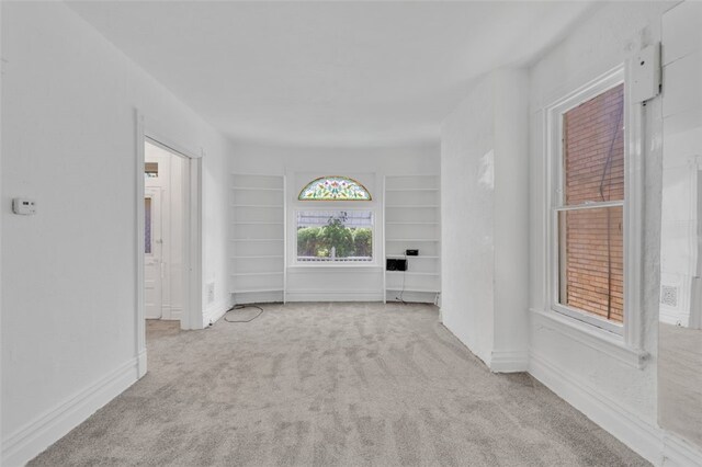 unfurnished living room featuring light carpet and built in features