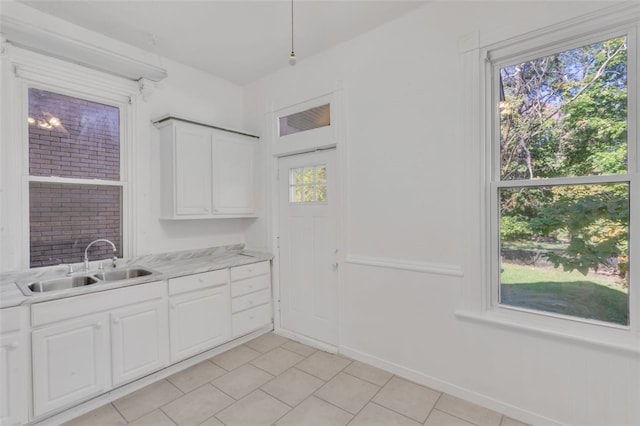 laundry area featuring light tile patterned floors, sink, and plenty of natural light