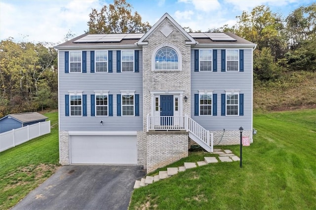 colonial inspired home featuring solar panels, a garage, and a front lawn