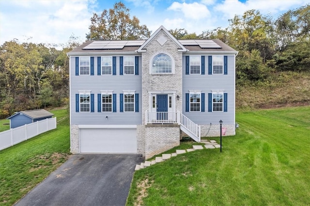 colonial inspired home with a garage, a front lawn, and solar panels