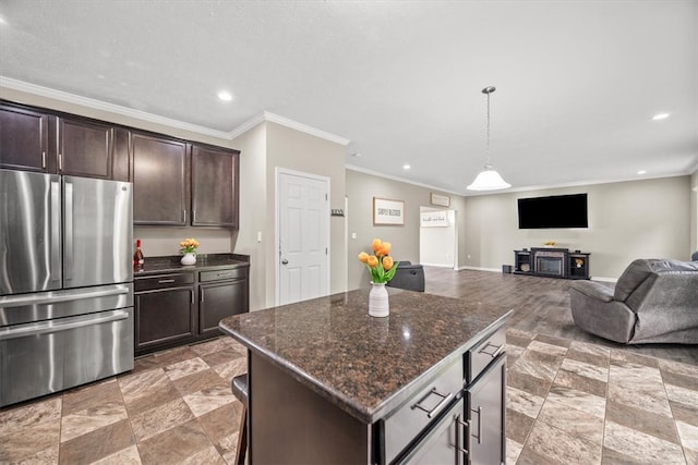 kitchen with hanging light fixtures, stainless steel refrigerator, dark stone countertops, dark brown cabinetry, and a center island