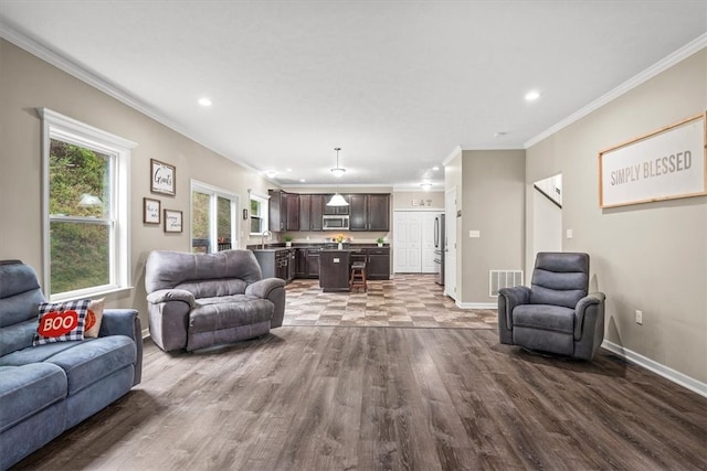 living room with dark wood-type flooring, crown molding, and sink