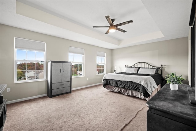 carpeted bedroom featuring a tray ceiling and ceiling fan