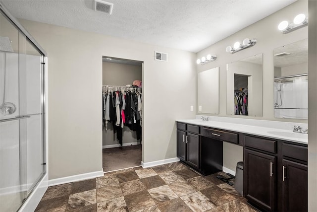 bathroom featuring vanity, a textured ceiling, and an enclosed shower