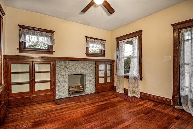 unfurnished living room featuring dark hardwood / wood-style floors, a fireplace, and ceiling fan