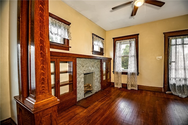 unfurnished living room featuring a high end fireplace, dark wood-type flooring, and ceiling fan