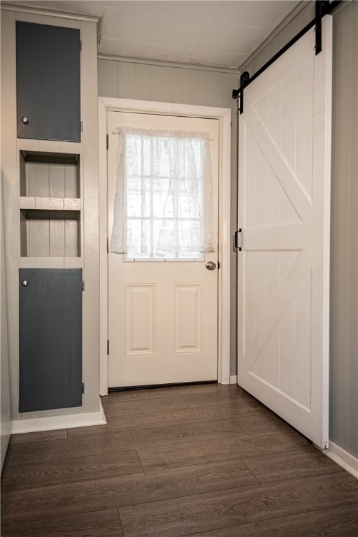 entryway featuring wood walls, dark hardwood / wood-style flooring, and a barn door