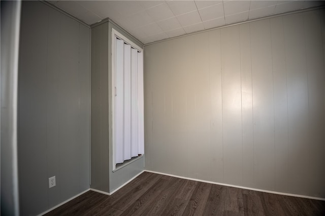 empty room with wood walls and dark hardwood / wood-style floors