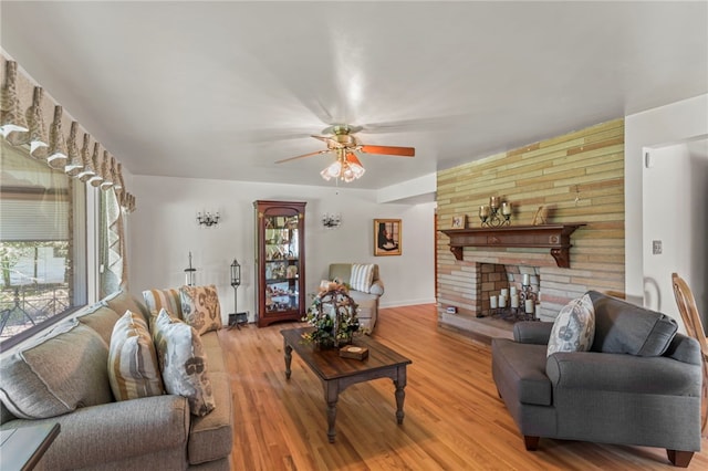 living room with a large fireplace, light hardwood / wood-style flooring, plenty of natural light, and ceiling fan