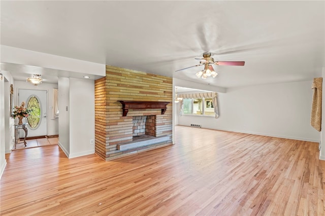 unfurnished living room featuring a brick fireplace, light wood-type flooring, and ceiling fan