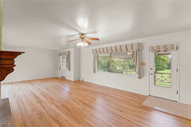 unfurnished living room featuring a healthy amount of sunlight, light hardwood / wood-style floors, and ceiling fan