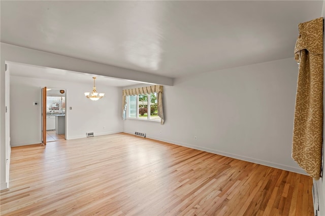 unfurnished living room with a notable chandelier, beamed ceiling, and light wood-type flooring